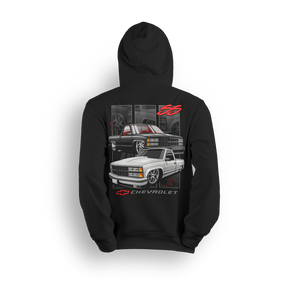 Dual Threat 454 SS hoodie featuring a blacked-out 454 SS and a clean white single cab, both dropped low with classic Chevy muscle style. Red interior accents, bold Chevrolet badge, and subtle interior panels complete this yin-yang inspired custom truck design.