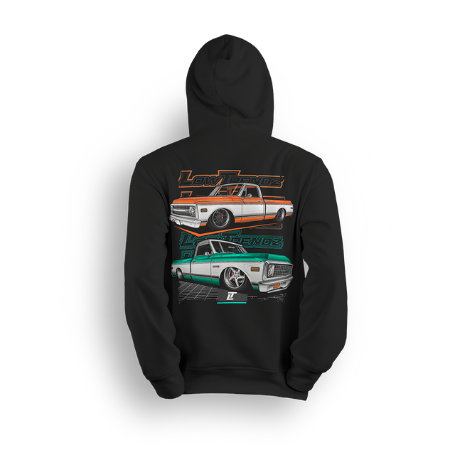 Hoodie featuring two slammed Chevy C10s in orange/white and mint/white two-tone colorways, laid out over a modern grid with layered Low Trendz branding. The Two-Tone Throwback hoodie blends vintage Chevy style with a clean, show-ready stance.