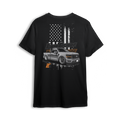 T-shirt featuring a slammed, murdered-out single cab Ford F-150 in front of a distressed American flag with burnt orange Low Trendz branding. The Stars, Stripes & Stance t-shirt delivers bold Ford energy and custom street presence for true lifestyle reps.