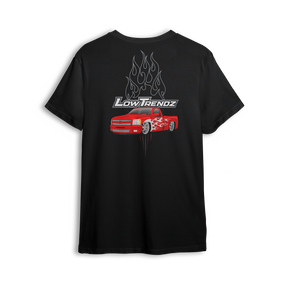 T-shirt featuring a slammed red Chevy truck with silver hot-rod flames down the sides and chrome flames bursting behind an oversized Low Trendz logo. The Flame Drop t-shirt brings high-octane energy and bold street presence.